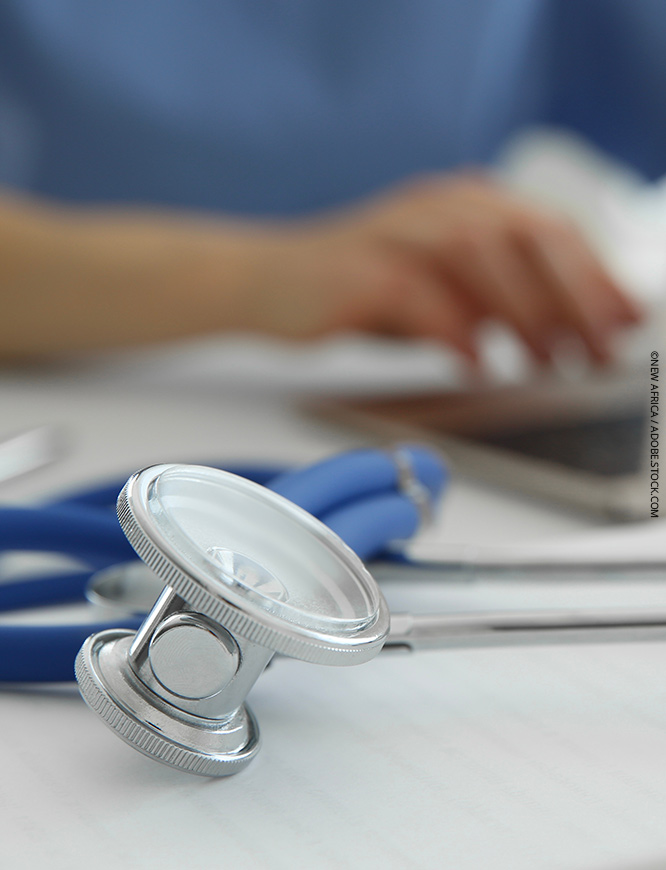 Symbolbild Früherkennung, Leistungen, Arzt am weißen Tisch, Fokus auf medizinischem Stethoskop
