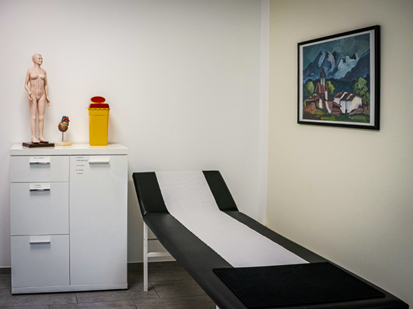 Behandlungsraum Praxis Dr. Schencking, mit Behandlungsliege und einem weißen Schrank