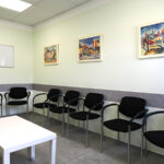 Wartezimmer der Praxis Dr. Schencking mit schwarzen Stühlen und 3 Aquarellen ander Wand