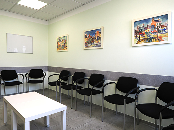 Wartezimmer der Praxis Dr. Schencking mit schwarzen Stühlen und 3 Aquarellen ander Wand